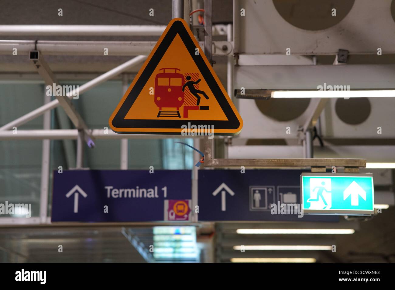 Panneau d'avertissement à une station de S-Bahn de Munich indiquant les dangers des trains et les indicateurs de direction du terminal 1 avec les feux de sortie de secours.Munich, Allemagne Banque D'Images