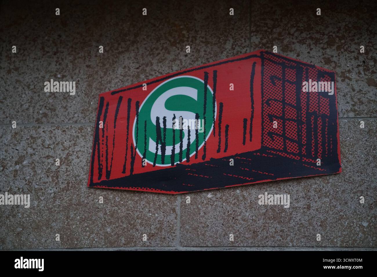 Logo graffiti S-Bahn sur un panneau rouge monté sur un mur texturé à la lumière du soir, représentant le réseau de métro de la ville.Westkreuz, Munich, Allemagne Banque D'Images
