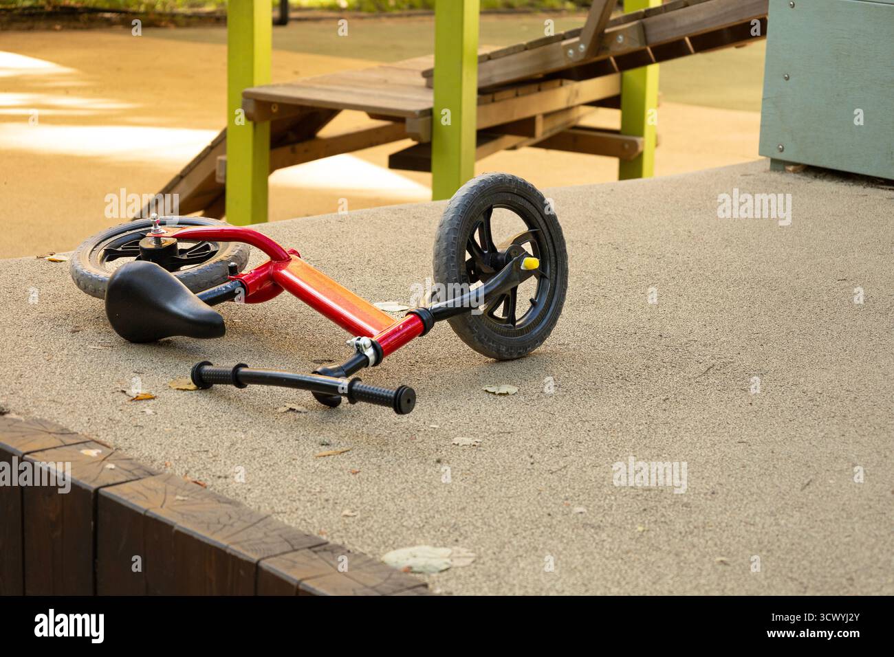 Vélo d'équilibre rouge abandonné sur le terrain de jeu Banque D'Images
