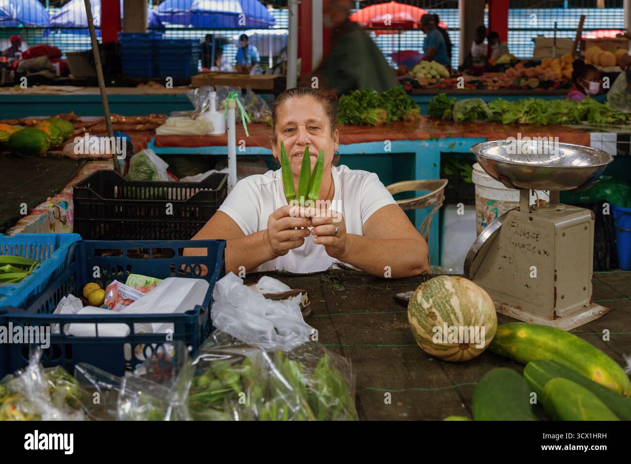 Vendeur local vendant des légumes et des fruits tropicaux au Victoria Market aux Seychelles, montrant la culture de l'île, les produits frais et la vie quotidienne. Banque D'Images
