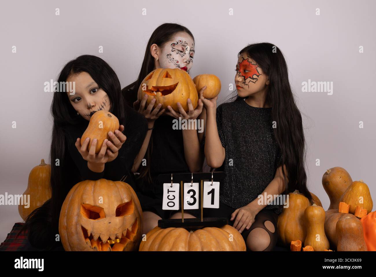 Filles avec des costumes d'Halloween tenant des citrouilles dans un cadre d'automne coloré Banque D'Images