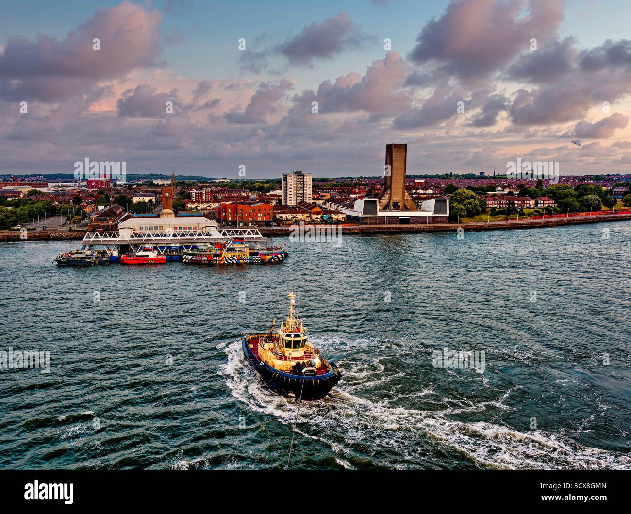 LIVERPOOL, ANGLETERRE - 18 août 2025 : un remorqueur passe devant le Mersey Ferry coloré amarré au terminal de ferry Woodside sur la rive de Wirral Banque D'Images