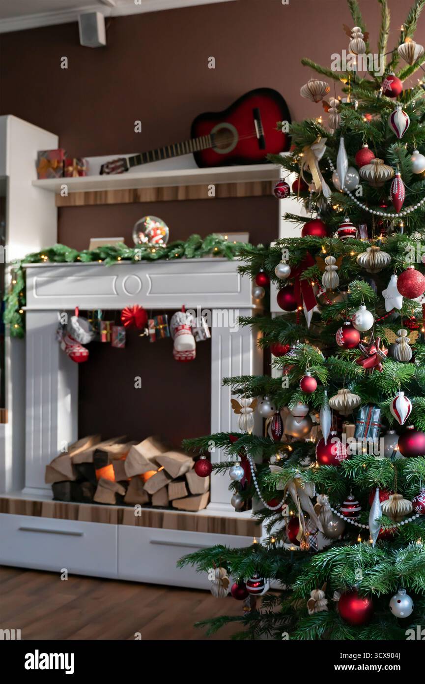 L'arbre de Noël dans le salon est décoré en rouge et blanc avec des ornements d'arbre de Noël en papier nid d'abeille. En arrière-plan se trouve un Fi électrique Banque D'Images