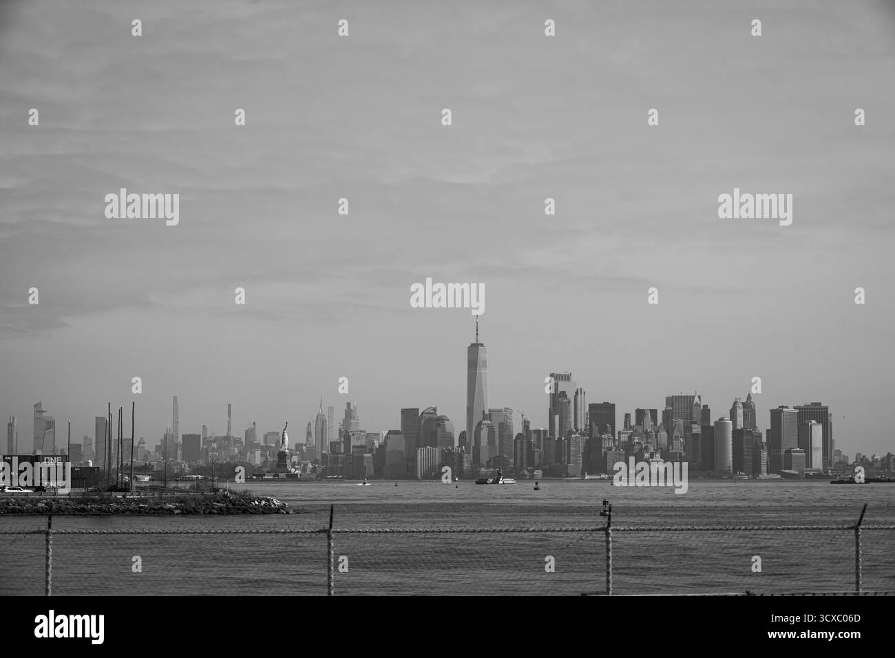 Bayonne, NJ, États-Unis – 14 mars 2025 : image spectaculaire en noir et blanc de l'horizon de Manhattan avec la Statue de la liberté au premier plan sous un s nuageux Banque D'Images