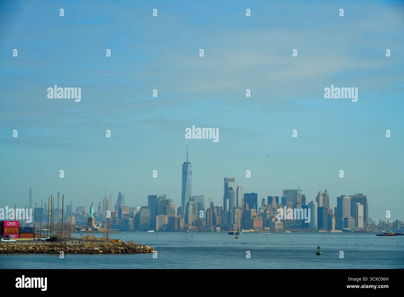 Bayonne, NJ, États-Unis – 14 mars 2025 : vue panoramique sur les gratte-ciel de Manhattan et la Statue de la liberté sous un ciel bleu, capturée à travers le fleuve Hudson Banque D'Images