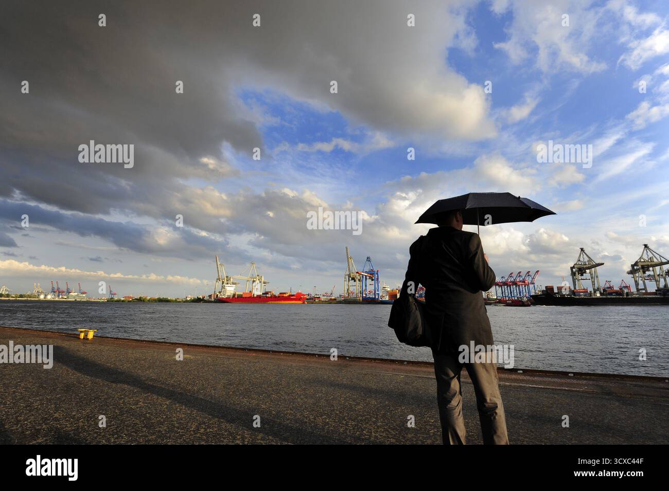 Homme avec parapluie, nuage de pluie sombre au-dessus du port de Hambourg, rivière Elbe, Oevelgoenne, ville hanséatique de Hambourg, Allemagne Banque D'Images