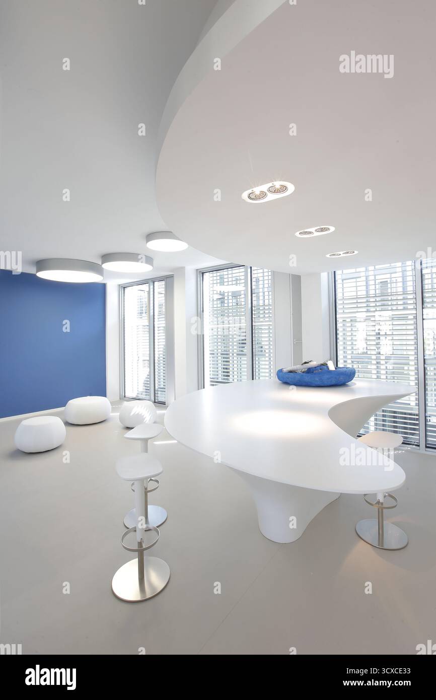 Salon moderne avec mobilier blanc et mur bleu, éclairé par des fenêtres lumineuses Banque D'Images