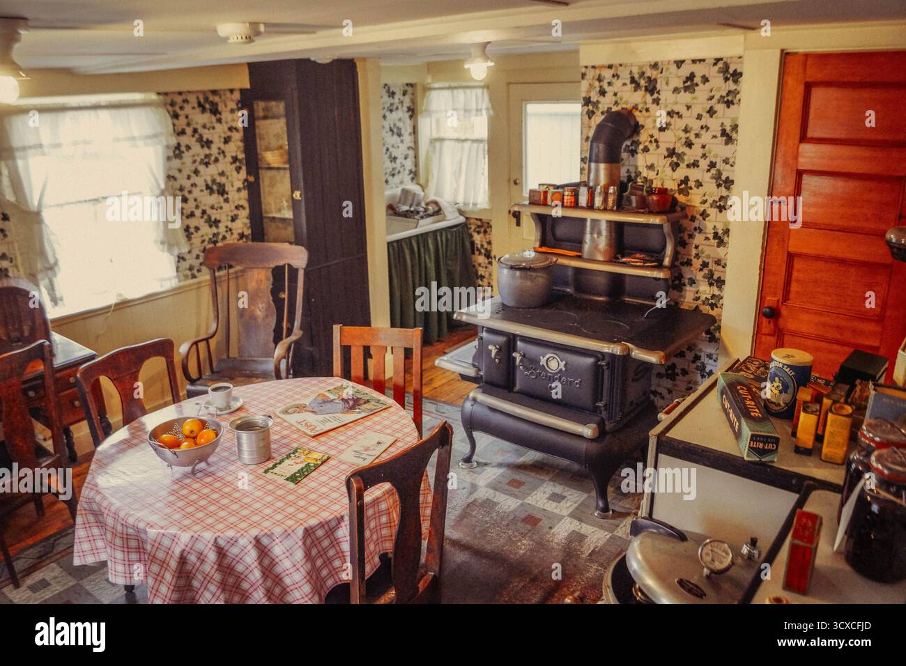 Intérieur de cuisine vintage à Strawbery Banke, Portsmouth, NH, avec vieux poêle, table en bois, papier peint floral et ustensiles historiques à la lumière du jour d'automne. Banque D'Images