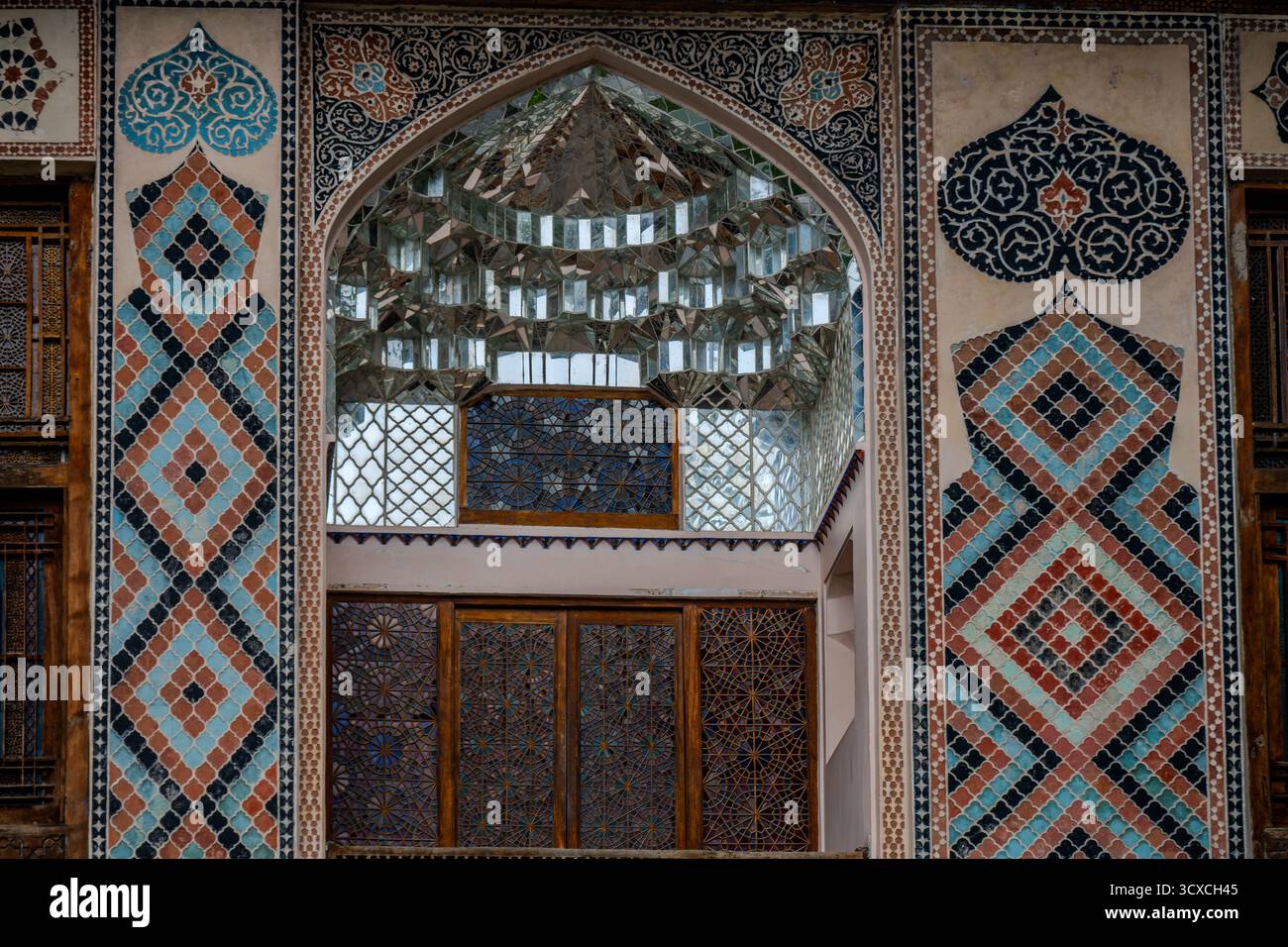 Gros plan sur les carreaux de mosaïque colorés, le plafond en miroir et les vitraux décorant l'arche ornée du palais Sheki Khan à Sheki, en Azerbaïdjan Banque D'Images