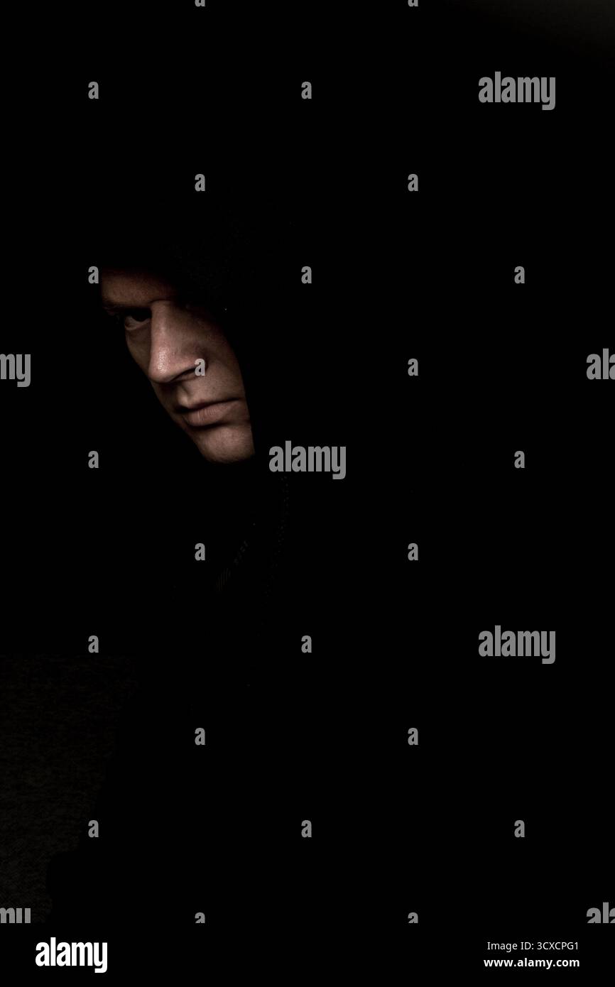 homme effrayant dans le sweat à capuche chemise noir regardant sinistre, sombre portrait effrayant Banque D'Images