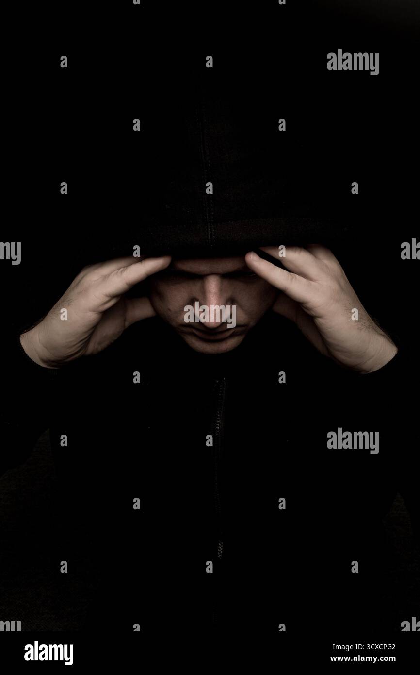 homme effrayant dans le sweat à capuche chemise noir regardant sinistre, sombre portrait effrayant Banque D'Images