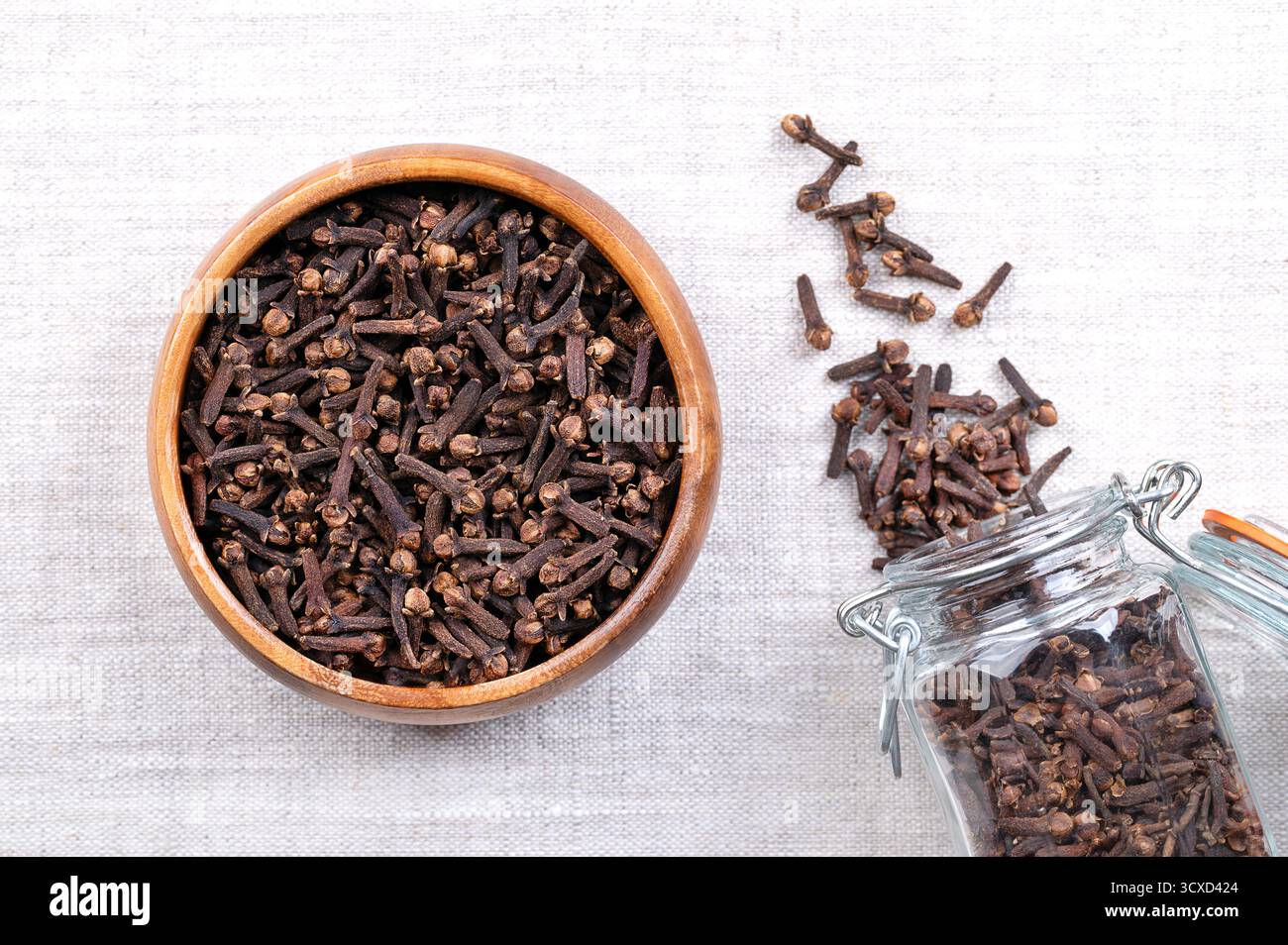 Clous de girofle séchés, dans un bol en bois, sur du lin. Boutons floraux aromatiques de l'arbre Syzygium aromaticum, utilisés comme épice, arôme ou parfum dans la cuisine. Banque D'Images Clous de girofle séchés, dans un bol en bois, sur du lin. Boutons floraux aromatiques de l'arbre Syzygium aromaticum, utilisés comme épice, arôme ou parfum dans la cuisine. Banque D'Images