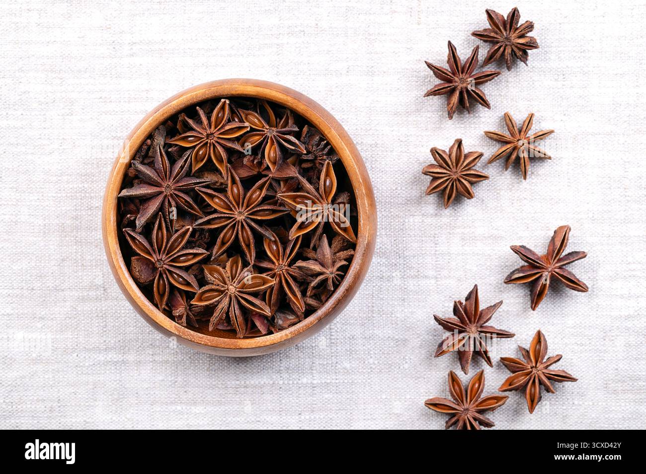 Graines d'anis étoilées dans un bol en bois sur lin. Fruits d'Illicium verum, également connu sous le nom de badian, anis étoilé chinois, anis étoilé. Banque D'Images