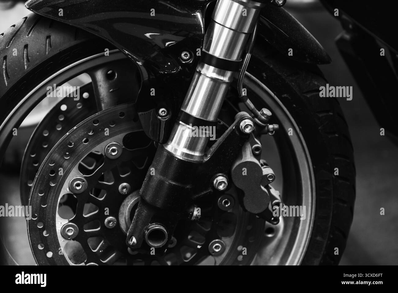 Gros plan détaillé en noir et blanc d'une roue avant de moto, d'un frein à disque et de fourches suspendues, de la vitesse de transport, de la puissance, et ide de précision d'ingénierie Banque D'Images