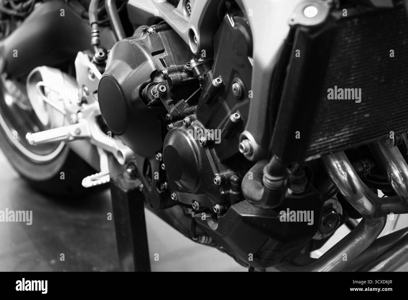 Une photo détaillée en noir et blanc mettant l'accent sur le moteur de la moto, les boulons et le cadre environnant. Met l'accent sur la précision mécanique, la texture et l'ingénierie Banque D'Images