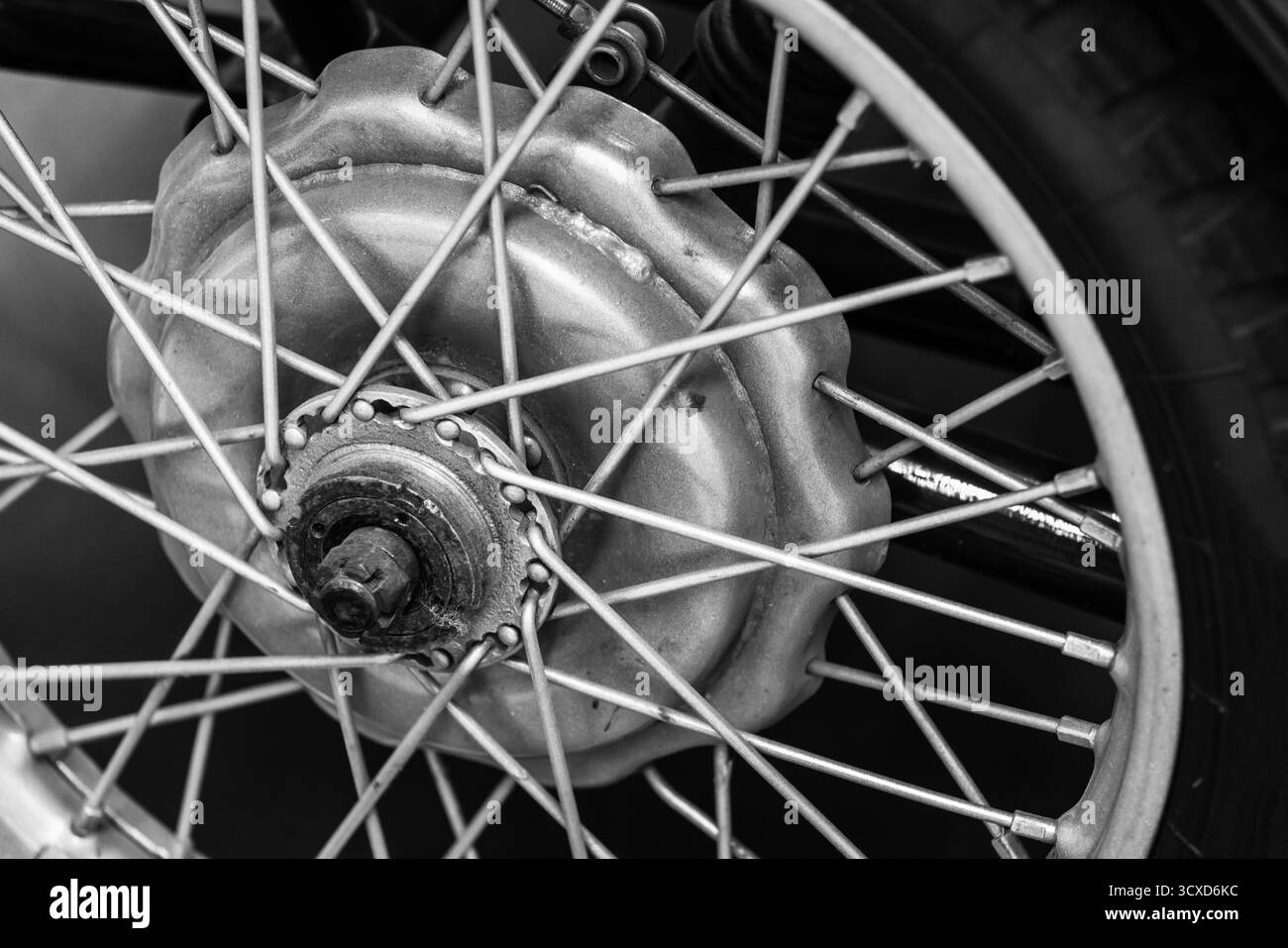 Vue détaillée en noir et blanc d'un moyeu de roue de moto, présentant les rayons, la jante et l'essieu. L'image monochrome souligne la texture métallique et Banque D'Images