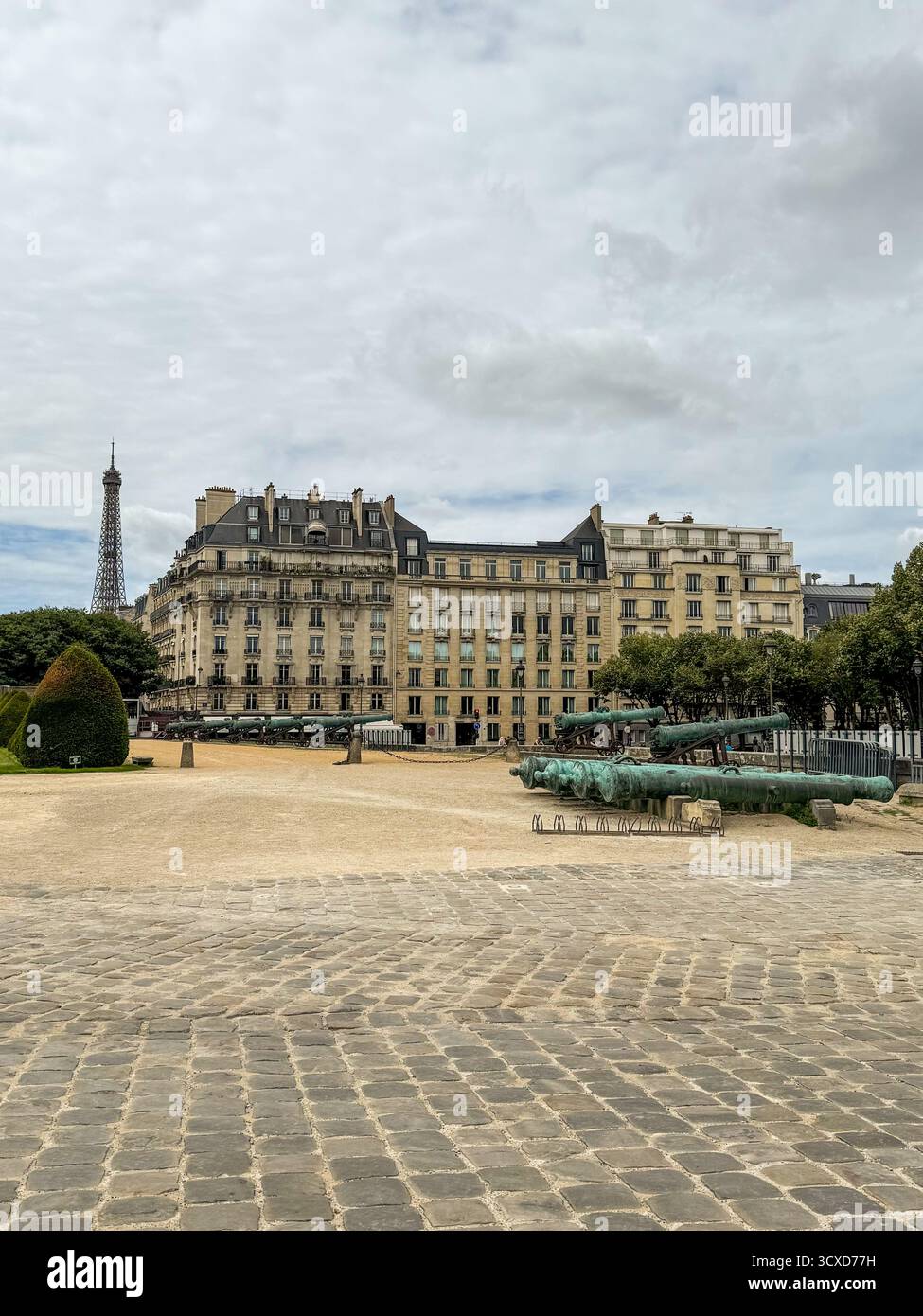Vue panoramique sur l'Esplanade des invalides à Paris, avec d'anciens canons militaires, des bâtiments haussmanniens et la lointaine Tour Eiffel - Image de stock capturée avec un smartphone