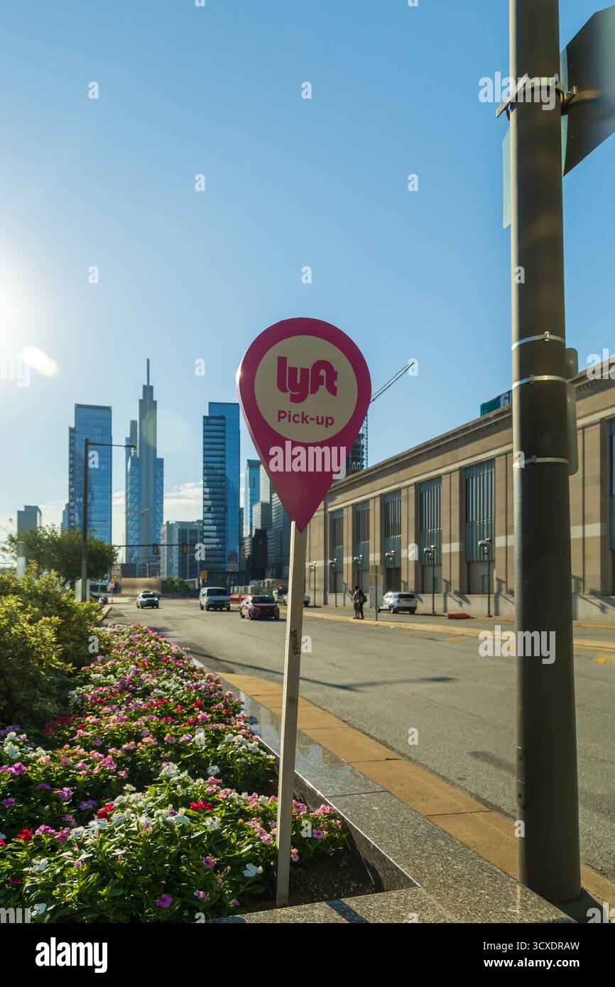 Un panneau LYFT rose est sur un poteau devant un bâtiment. Le panneau est sur une rue avec des voitures et quelques personnes, Philadelphie, USA Banque D'Images Un panneau LYFT rose est sur un poteau devant un bâtiment. Le panneau est sur une rue avec des voitures et quelques personnes, Philadelphie, USA Banque D'Images