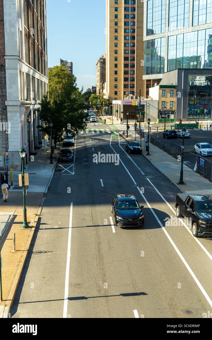 Une rue animée de la ville avec des voitures et des piétons. Les voitures sont noires et la rue est bordée de grands bâtiments, Philadelphie, USA Banque D'Images Une rue animée de la ville avec des voitures et des piétons. Les voitures sont noires et la rue est bordée de grands bâtiments, Philadelphie, USA Banque D'Images