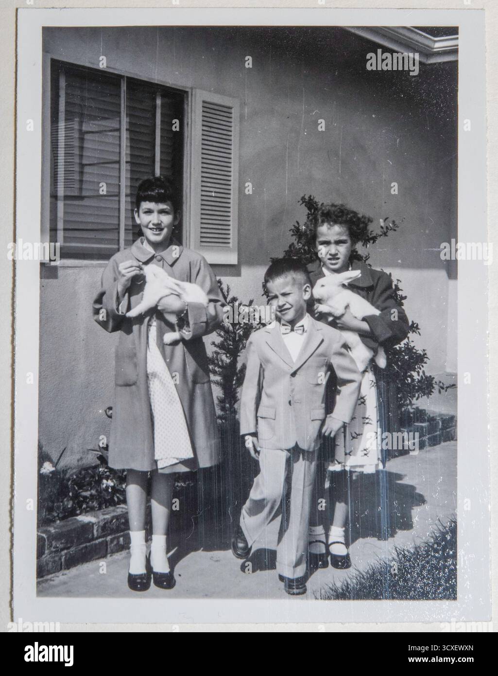 Les enfants posent avec leurs lapins vivants lors d'une célébration de Pâques devant leur maison résidentielle, Sacramento, Californie, 1957, États-Unis Banque D'Images