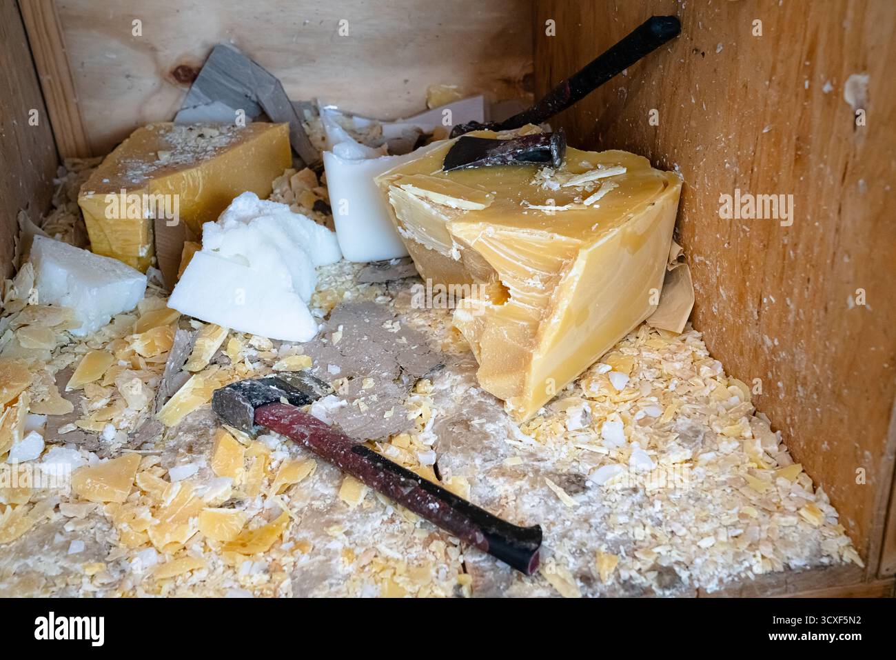 Détail des morceaux de cire d'abeille jaunes et blanches coupés et préparés pour le traitement dans un atelier de production de cire durable Banque D'Images