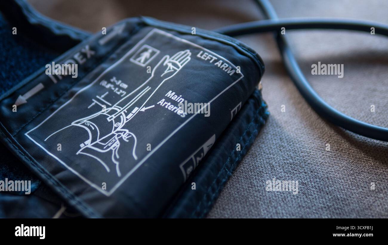 Gros plan d'un brassard de tensiométrie avec schéma anatomique et instructions étiquetées pour mesurer la pression artérielle sur le bras gauche. Banque D'Images