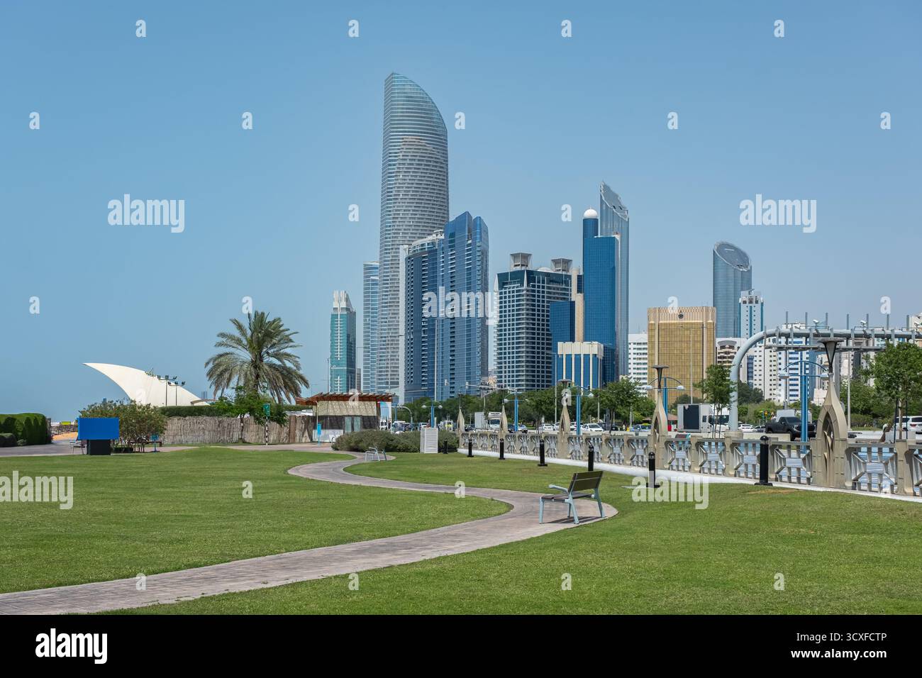 Belle passerelle dans le parc urbain de la ville avec des arbres verts. Vue sur la promenade de la Corniche à Abu Dhabi, Émirats arabes Unis. Parc de plage boulevard Corniche le long de la côte Banque D'Images