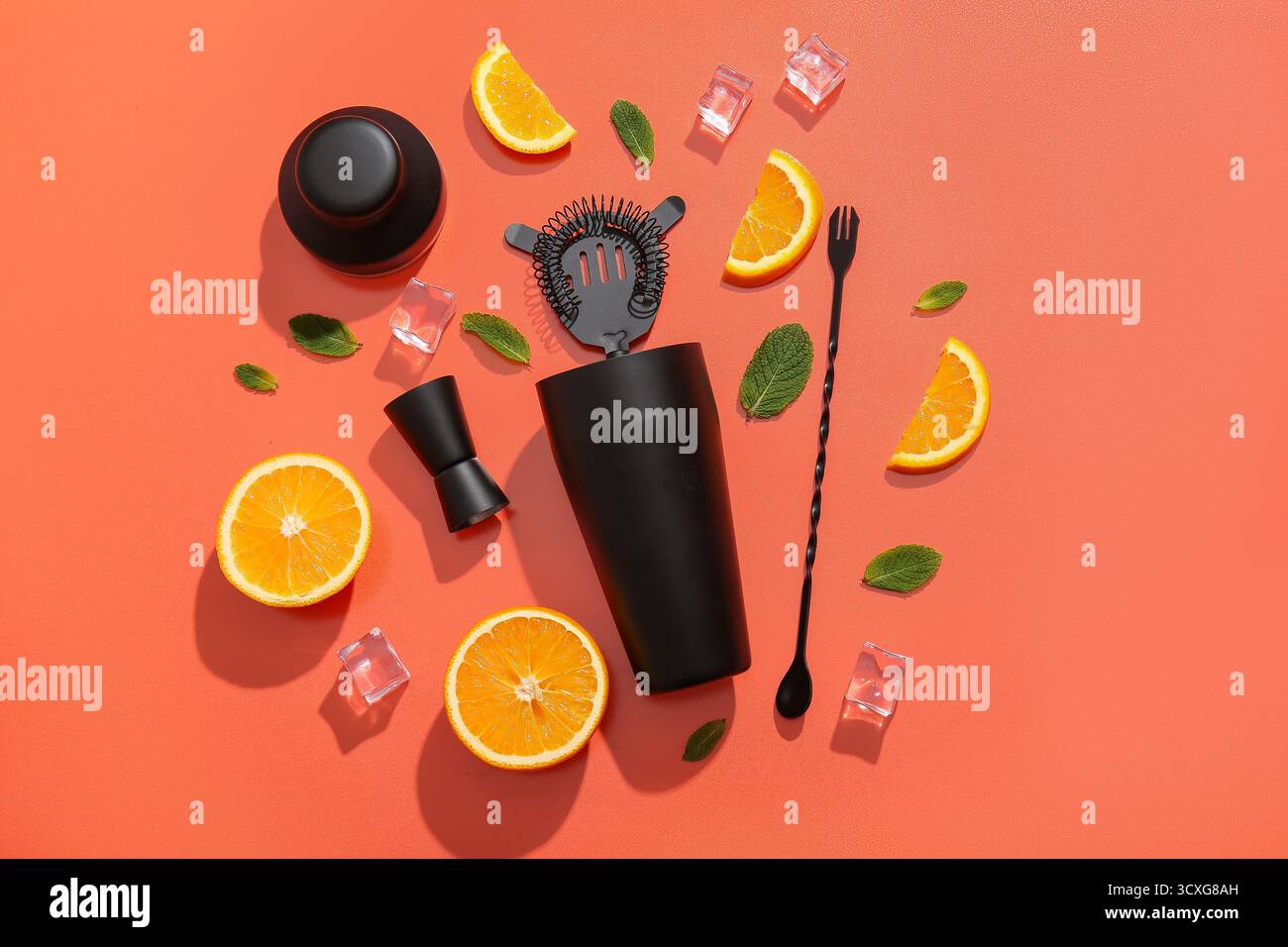 Ustensiles de barman avec tranches d'orange, glaçons et feuilles de menthe sur fond rouge Banque D'Images