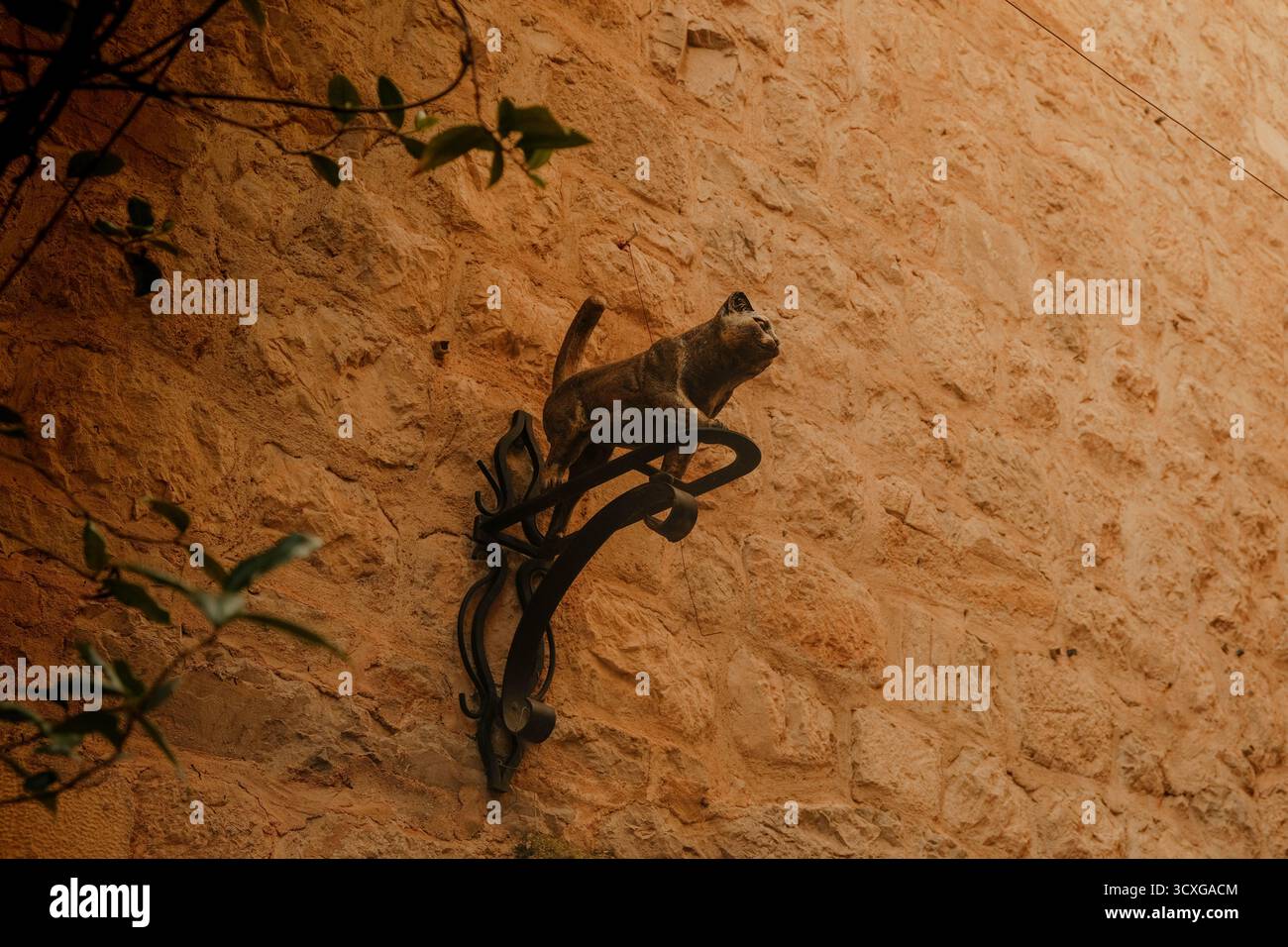 Sculpture en métal d'un chat monté sur un mur de pierre dans une ville historique Banque D'Images