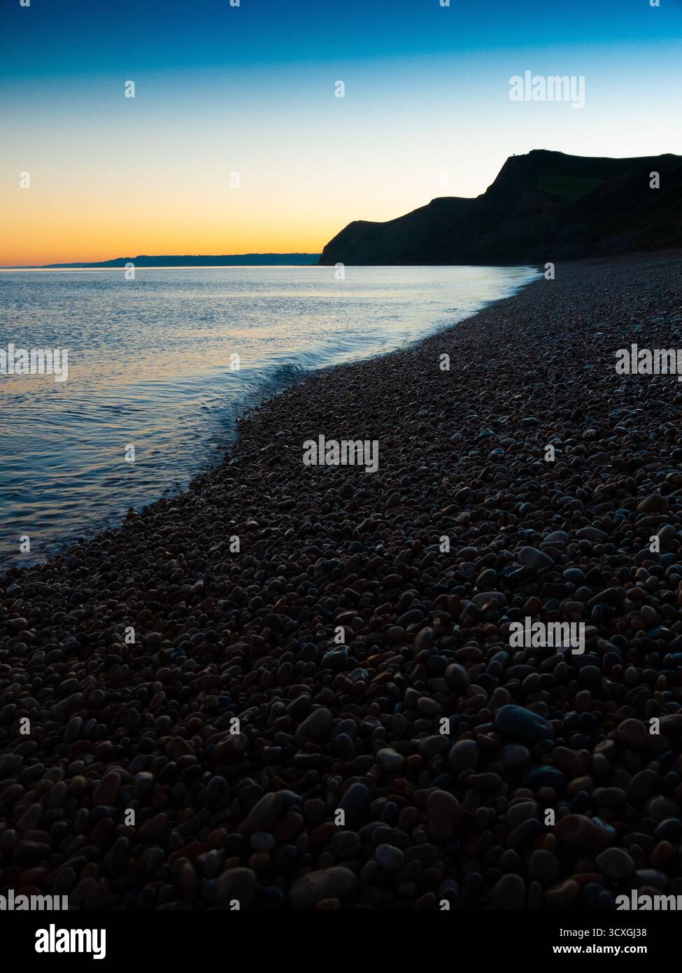 Plage de galets au coucher du soleil avec falaises spectaculaires et mer calme le long de la côte du Dorset Banque D'Images Plage de galets au coucher du soleil avec falaises spectaculaires et mer calme le long de la côte du Dorset Banque D'Images