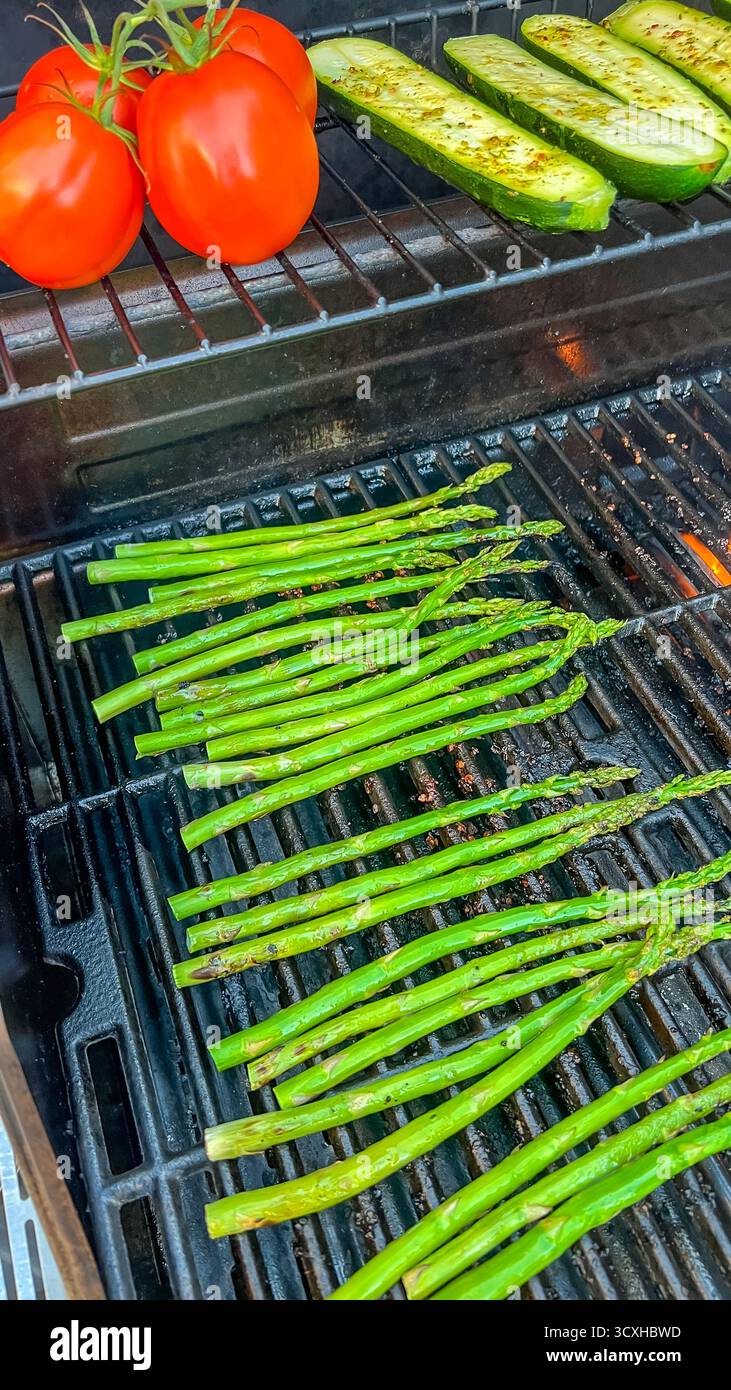 Asperges, tomates et concombres grillés sur un barbecue, mettant en valeur les ingrédients frais et les méthodes de cuisson saines dans un cadre extérieur Banque D'Images