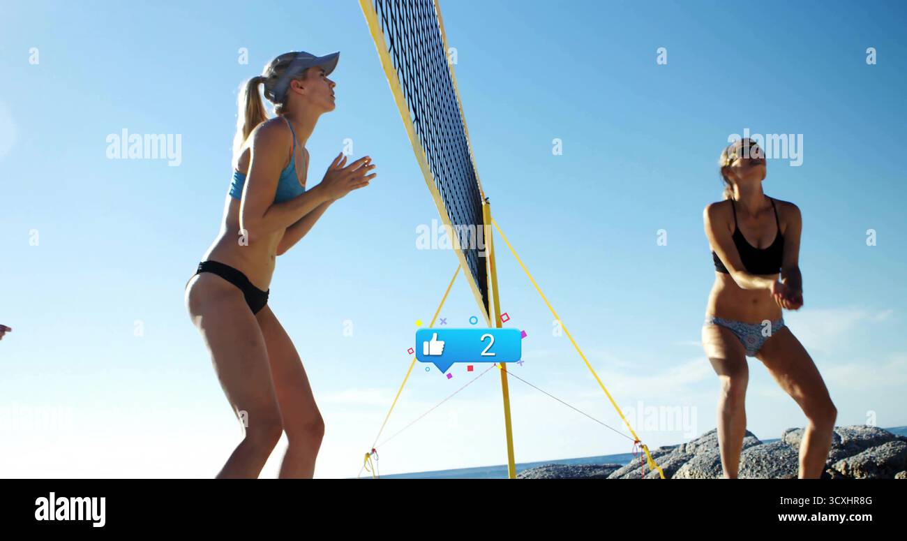 Positionnement de deux athlètes féminines en maillot de bain face à la plage rocheuse avec filet de volley portable Banque D'Images