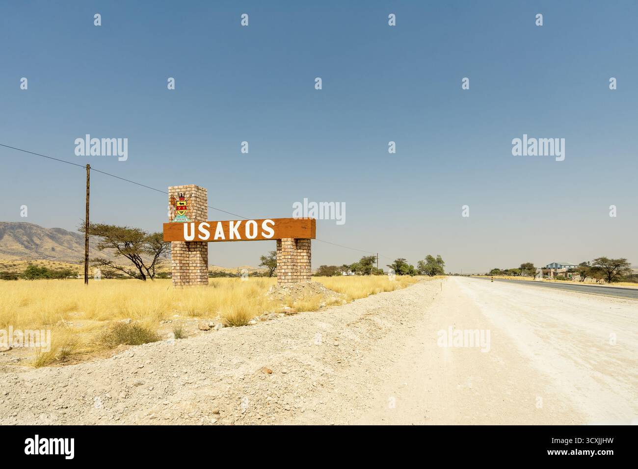 Une vue panoramique d'un panneau de signalisation indiquant Usakos, Namibie - 2 septembre, face à un ciel bleu vif et une route ouverte. L'image capture l'essence de Banque D'Images