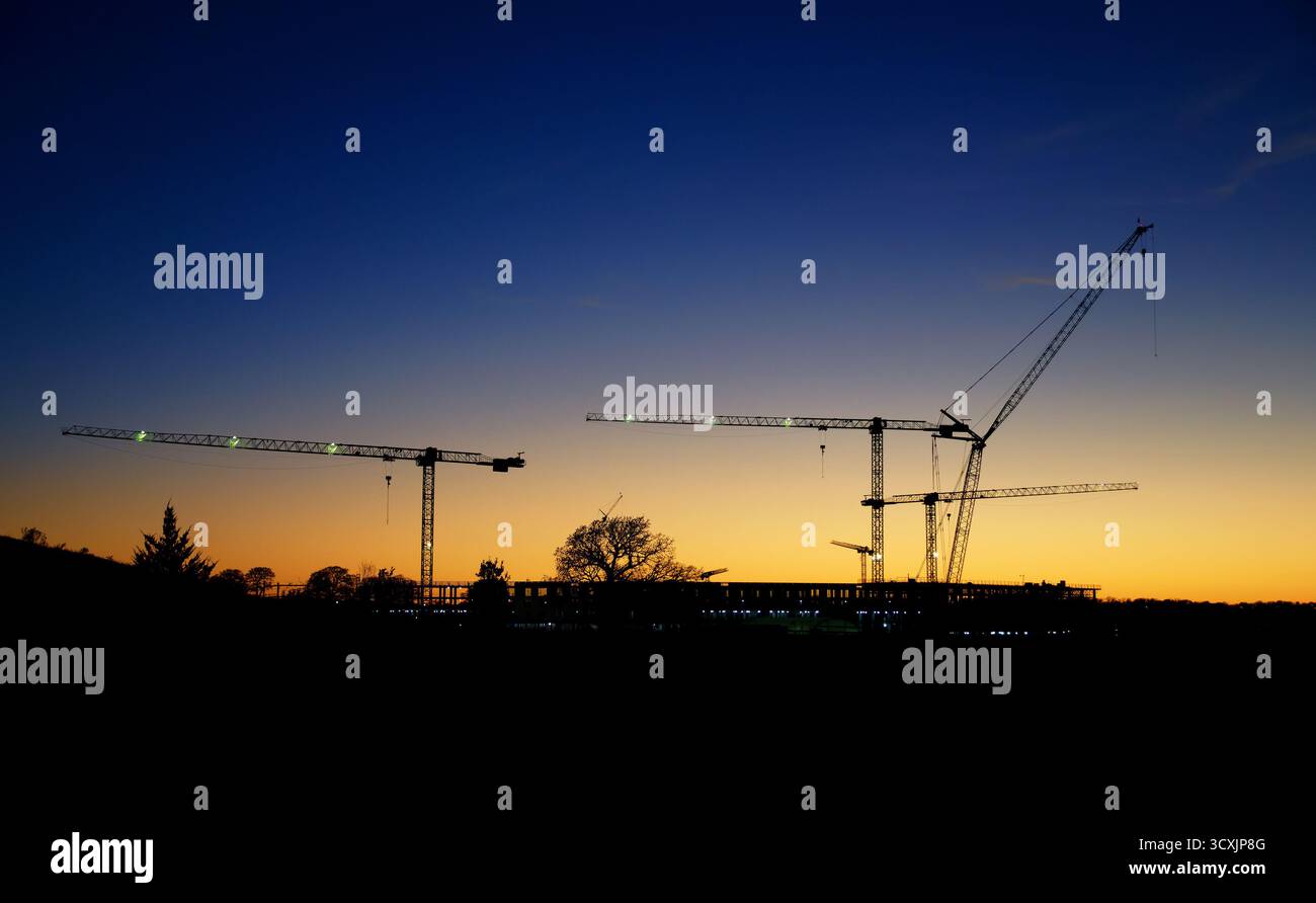 Silhouettes de grues de construction contre beau ciel de coucher de soleil du soir. Copier l'espace. Banque D'Images