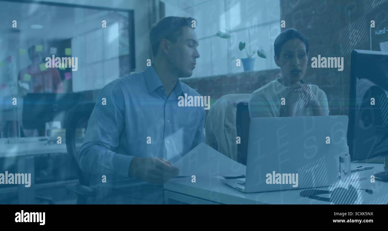 Des collègues de bureau examinant des documents imprimés et des écrans de contrôle au bureau, avec ordinateur portable et notes adhésives Banque D'Images