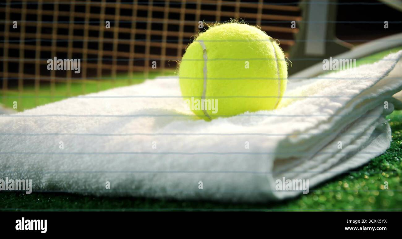 Balle de tennis reposant sur une serviette blanche au court de tennis, avec filet de tennis orange, poteau en métal Banque D'Images
