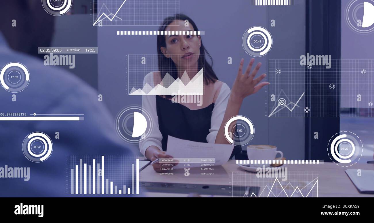 Gestuelle exécutif présentant des données à la table de conférence, avec des documents imprimés et des graphiques numériques Banque D'Images