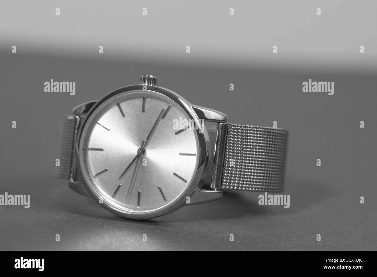 Une montre argentée avec un visage noir se trouve sur une surface grise. La montre est réglée sur 10 h 10 Banque D'Images