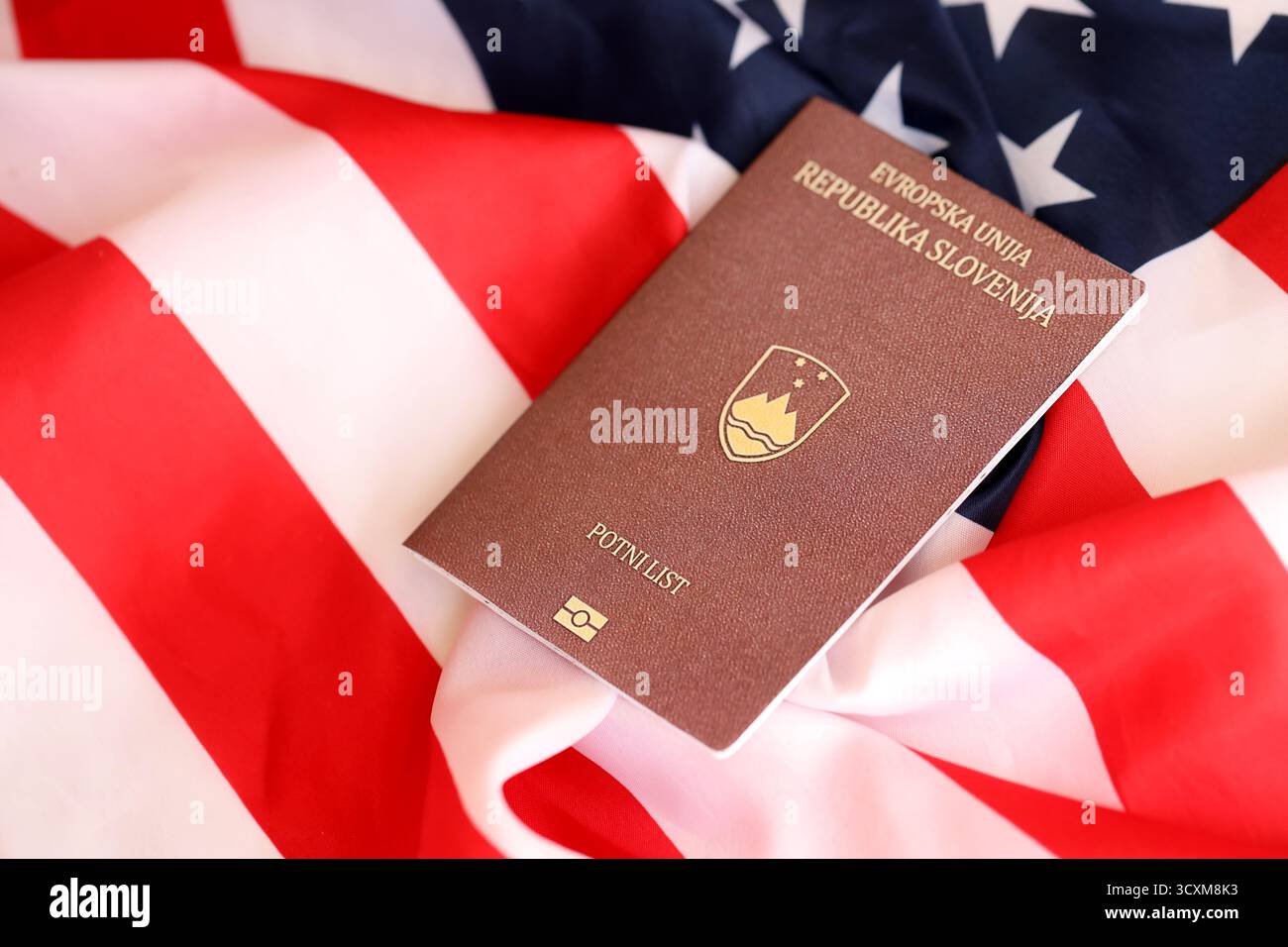 Passeport slovène sur grand drapeau agitant des États-Unis d'Amérique close up. Visa AMÉRICAIN et concept d'immigration Banque D'Images