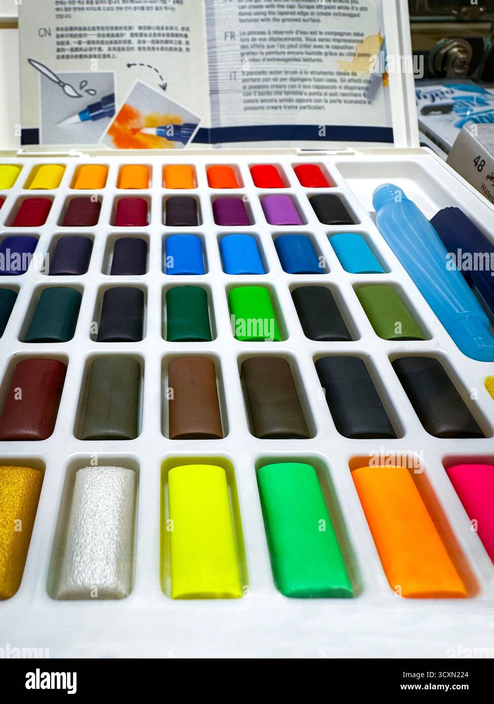 Un ensemble vibrant de peintures aquarelles colorées disposées soigneusement dans un plateau en plastique avec un dépliant affichage de détail kuala lumpur malaisie - Image de stock capturée avec un smartphone