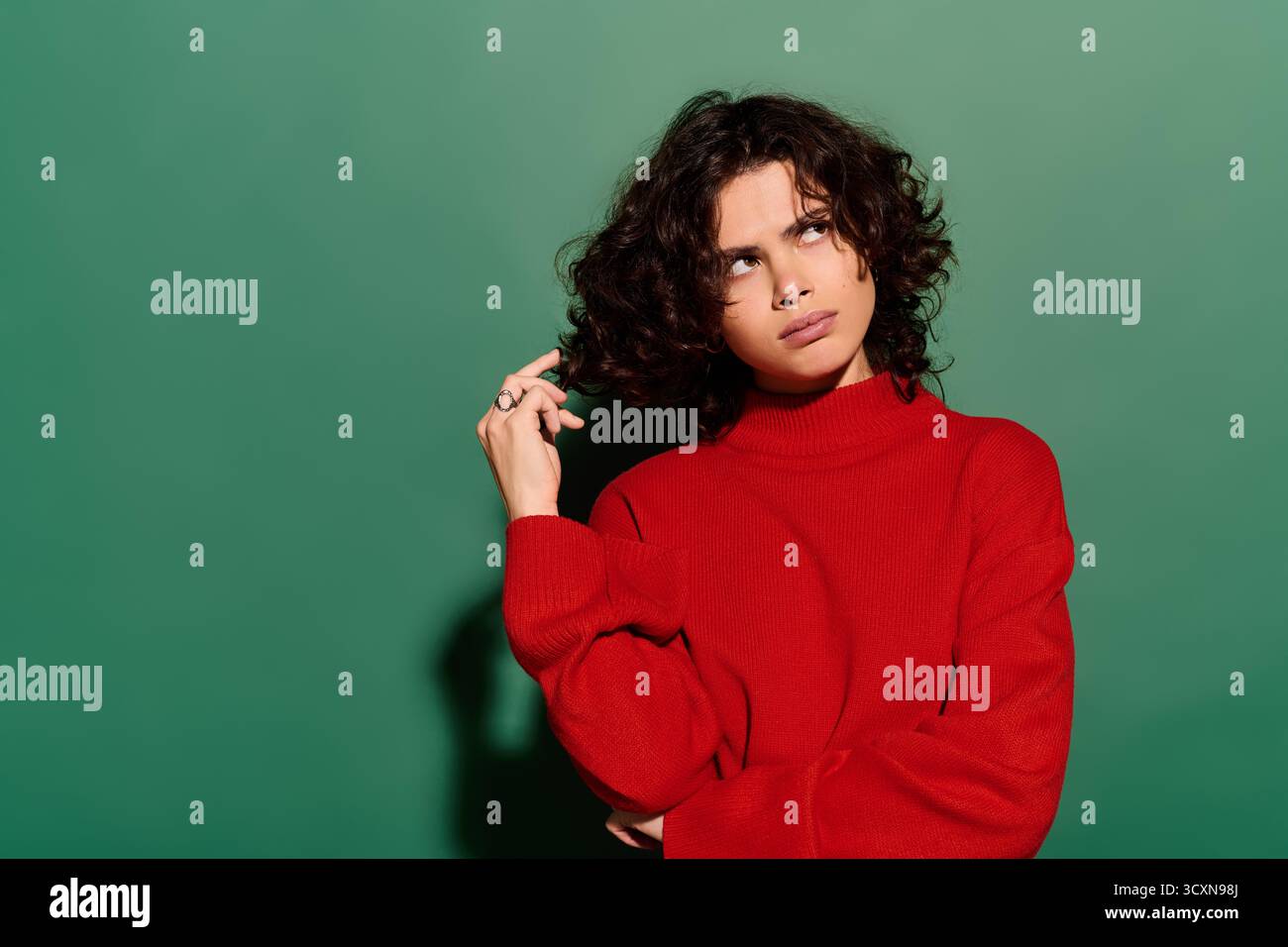 Belle femme aux cheveux bouclés pose soigneusement tout en montrant son style unique et sa confiance. Banque D'Images