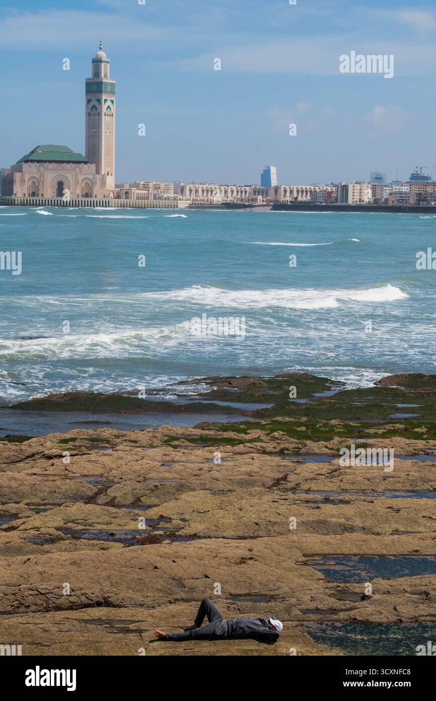 Casablanca, Maroc, Afrique : homme avec une balle de baseball reposant sur la plage pendant le ramadan ramadan devant l'océan Atlantique et la mosquée Hassan II (1993) Banque D'Images