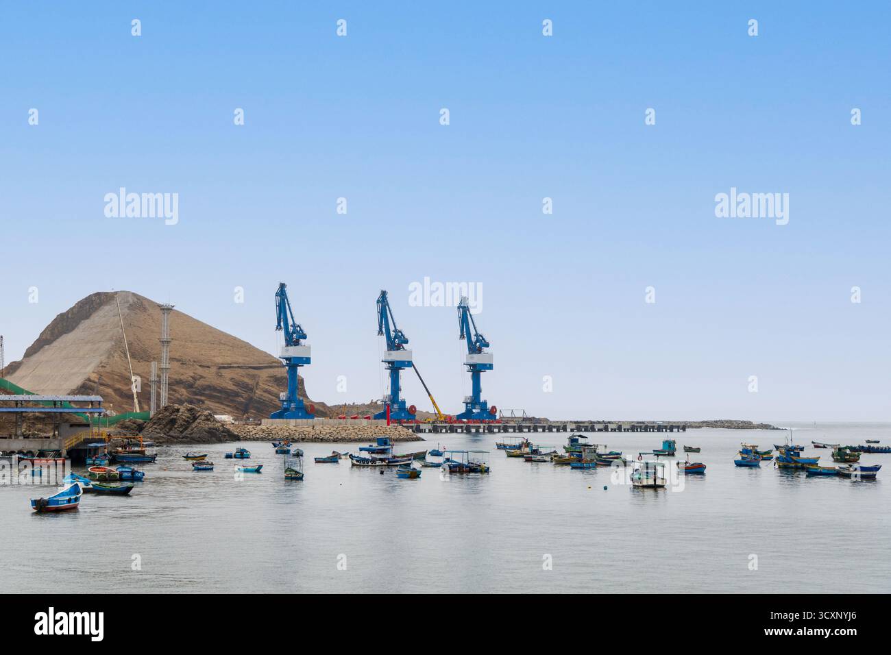 Méga port de Chancay. Une grande grue bleue se trouve au milieu d'un port avec de nombreux bateaux. Le port est plein de bateaux de toutes tailles, et le ciel est dégagé et Banque D'Images Méga port de Chancay. Une grande grue bleue se trouve au milieu d'un port avec de nombreux bateaux. Le port est plein de bateaux de toutes tailles, et le ciel est dégagé et Banque D'Images