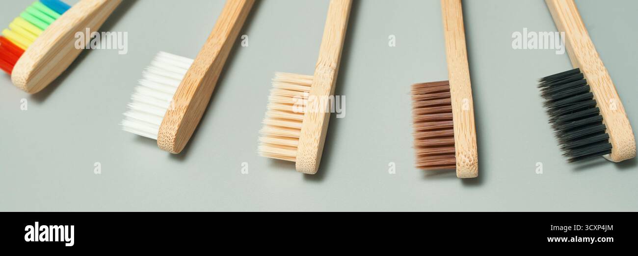 Brosses à dents écologiques en bambou avec des poils colorés et naturels sur fond gris. Banque D'Images