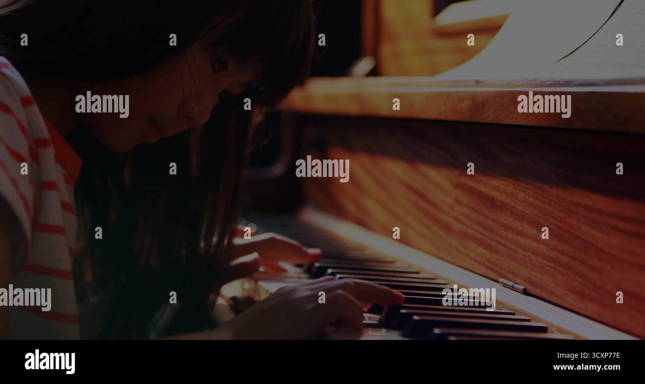 Fille chinoise jouant du piano dans le coin de la musique à la maison, avec partition sur le stand, espace de copie Banque D'Images