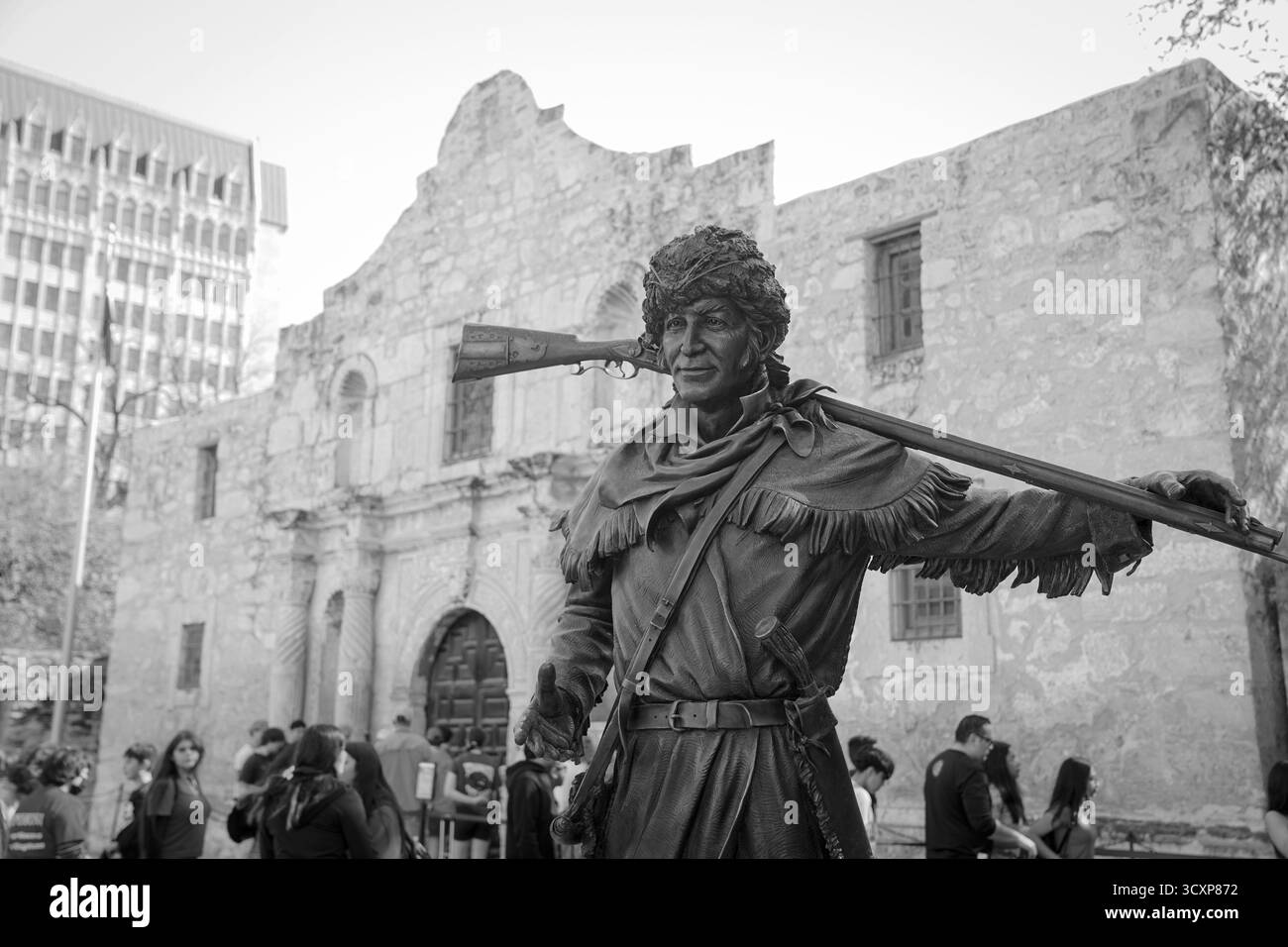 Image en noir et blanc de la statue de Davy Crockett devant la mission Alamo, capturant le monument historique et ses visiteurs en monochrome intemporel Banque D'Images