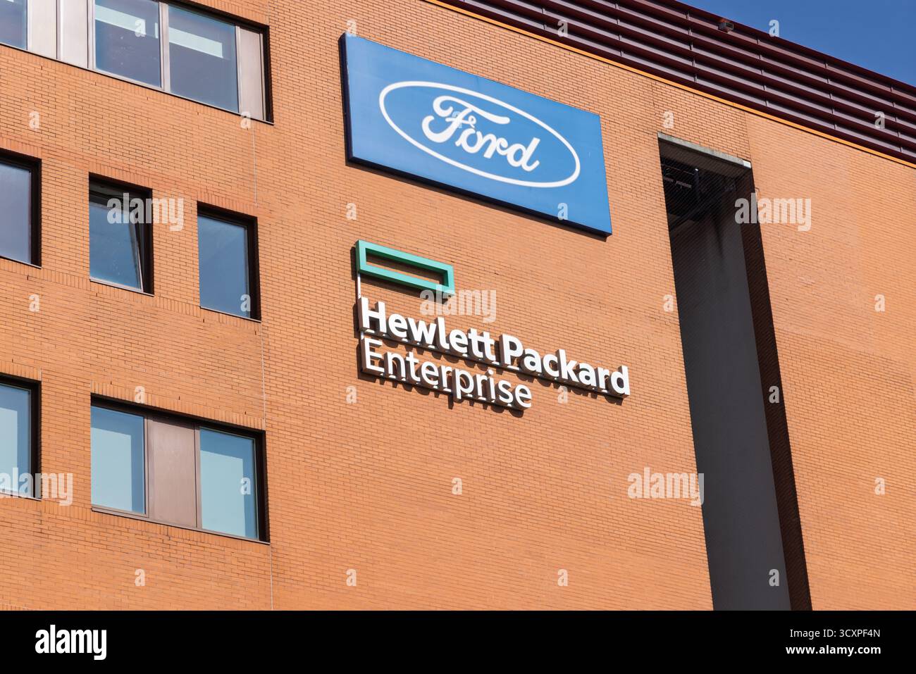 Le logo Hewlett Packard Enterprise et un logo Ford séparé affichés sur la façade d'un grand immeuble de bureaux en briques à Amstelveen, pays-Bas. Amstelveen, Banque D'Images