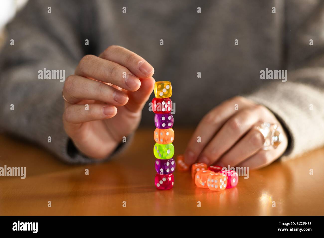 Mains féminines empilant soigneusement des dés colorés en forme de pyramide sur une table. Concept d'équilibre de mise au point et de créativité. Banque D'Images