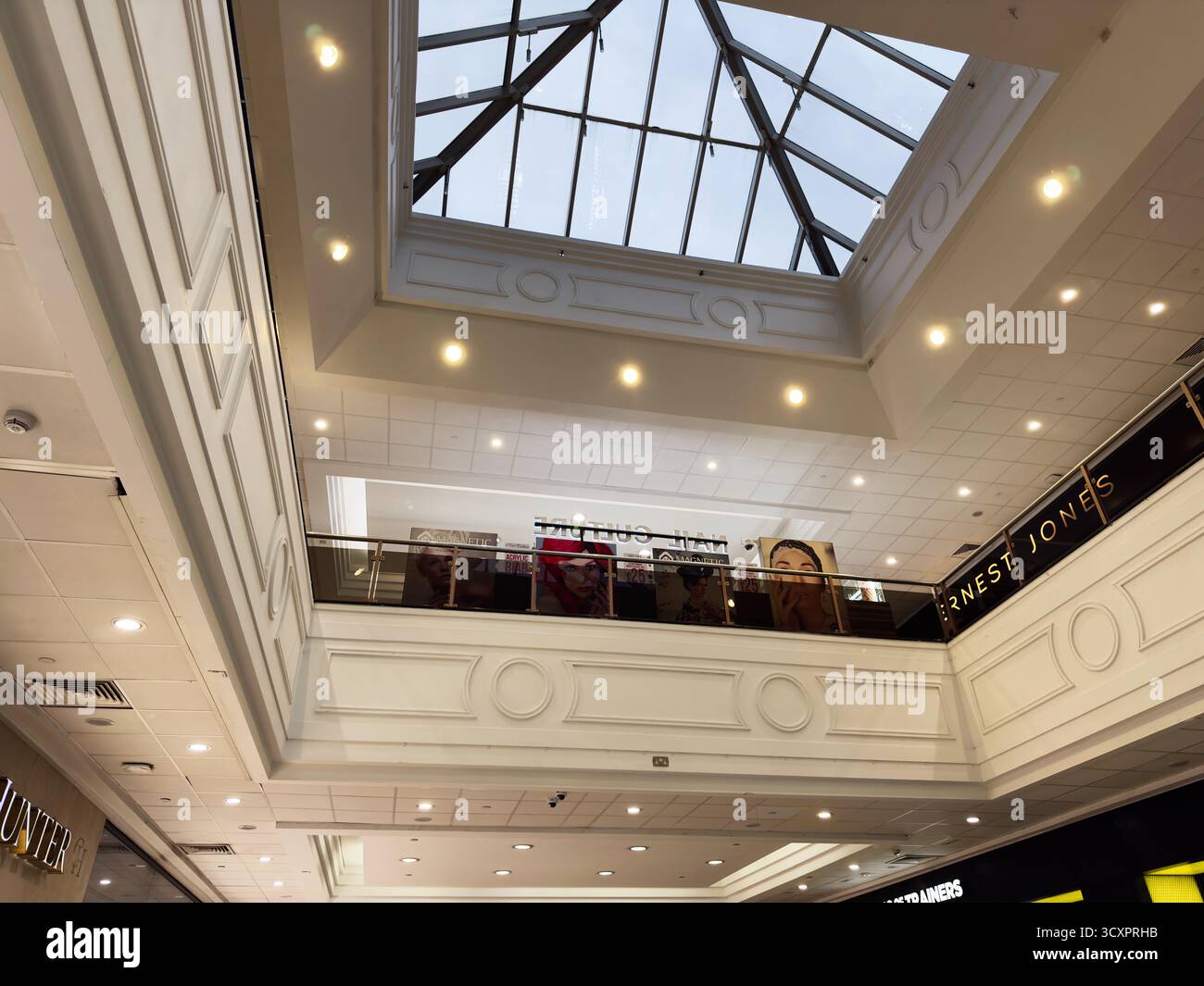 Manchester, Royaume-Uni - 26 septembre 2025 : atrium lumineux du centre commercial Arndale avec puits de lumière en verre, panneaux blancs et devantures de magasins au niveau supérieur. Banque D'Images