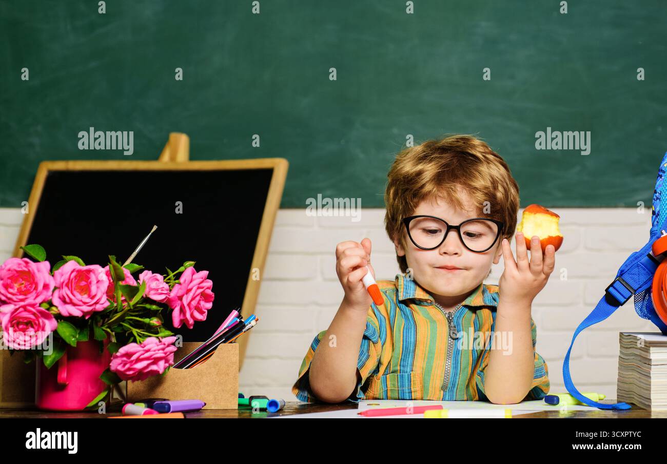 Déjeuner scolaire. Enfant assis à table et mange de la nourriture saine pendant la pause à l'école. Élève de l'école primaire à l'heure du déjeuner en classe. Mignon écolier dedans Banque D'Images